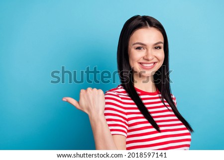 Photo of young sweet charming smiling girl point thumb copyspace product promotion isolated on blue color background