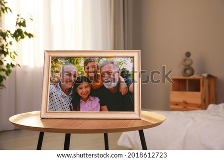 Framed family photo on wooden table in bedroom