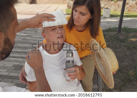 People helping mature woman on city street. Suffering from heat stroke Royalty-Free Stock Photo #2018612795
