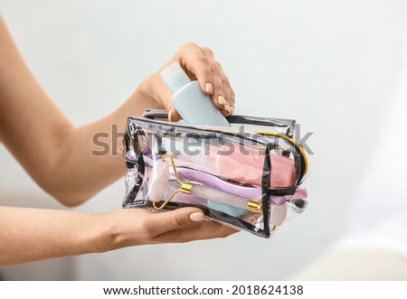Female hands and cosmetics bag on light background Royalty-Free Stock Photo #2018624138