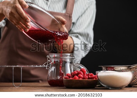 Woman cooking sweet raspberry jam in kitchen Royalty-Free Stock Photo #2018632103