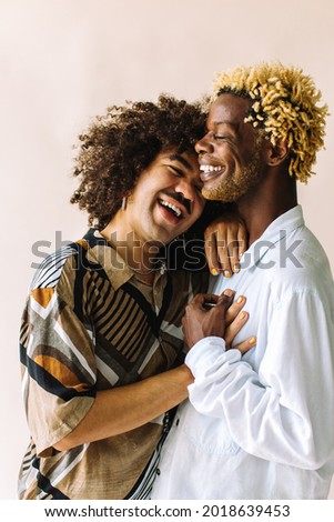 Carefree young gay couple standing together in a studio. Two affectionate male lovers smiling cheerfully while embracing each other against a studio background. Young gay coupe being romantic. Royalty-Free Stock Photo #2018639453