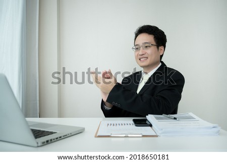 Happy Asian businessman making a online video conference while working from home. Asian young CEO clapping after finished the online meeting. Work from home concept.