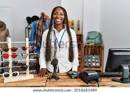Young african american shopkeeper woman smiling happy standing by the counter at clothing store. Royalty-Free Stock Photo #2018681489