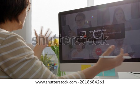 Back view mature middle-aged asian woman employee work from home use computer desktop pc videocall webinar conference angry annoy in low poor unreliable bad wifi connection slow issue outage. Royalty-Free Stock Photo #2018684261