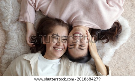Attractive beautiful cheerful authentic real family two people laying down look at camera above tender emotion hug kiss cuddle relax comfort sleep in living room in health care healthy mother day.