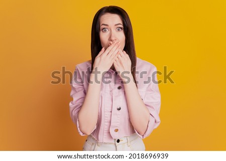Portrait of attractive woman closed mouth palms over yellow background