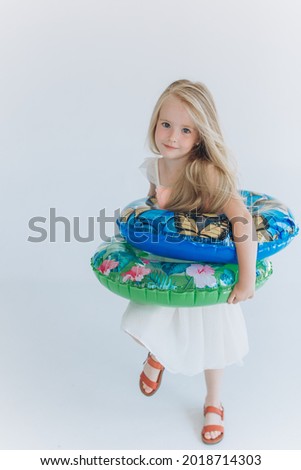 Happy emotional little blondie caucasian girl smiling witn inflatable ring on isolated white background