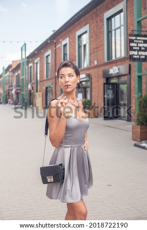 A beautiful girl walks around a big city in a lilac dress. Good weather