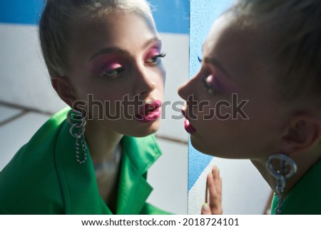 Woman with bright pink makeup looking attentively at the mirror while posing Royalty-Free Stock Photo #2018724101