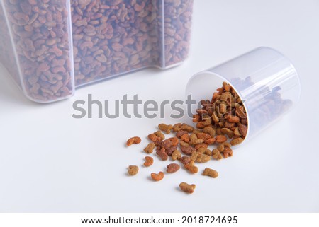 Animal feed, Ready to eat pellets food multi nutrients for cat and dogs or pet, Dried storage or Container box with measuring cup on white background.