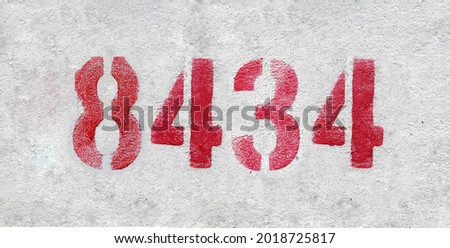 Red Number 8434 on the white wall. Spray paint. Number eight thousand four hundred thirty four.