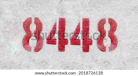 Red Number 8448 on the white wall. Spray paint. Number eight thousand four hundred and forty eight.