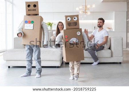 Happy family of parents and two children playing dancing like robots at home, children wearing handmade moving box costume of cardboard Royalty-Free Stock Photo #2018759225