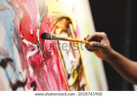 Close up of african american male painter at work painting on canvas in art studio. creation and inspiration at an artists painting studio. Royalty-Free Stock Photo #2018765900