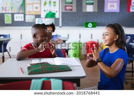 African american female teacher and boy talking in hand sign language at elementary school. school and education concept