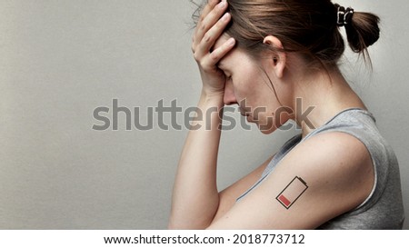 A tired woman and a picture of a dead battery on her. A symbol of lack of energy and fatigue in a person Royalty-Free Stock Photo #2018773712