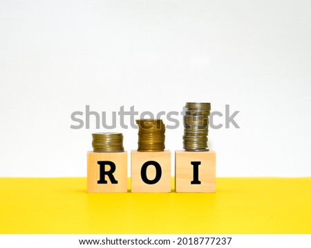 Wooden blocks with text "ROI" and coins. Business concept.