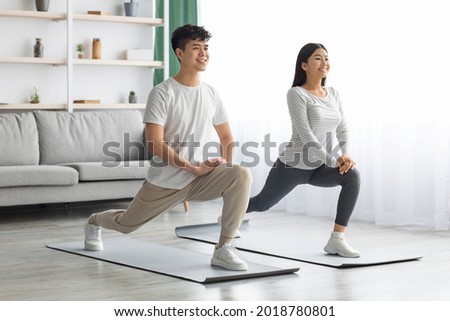 Motivated asian young couple exercising together at home, positive korean man and woman in sportswear standing on fitness mat, stretching and smiling, copy space. Healthy lifestyle concept Royalty-Free Stock Photo #2018780801