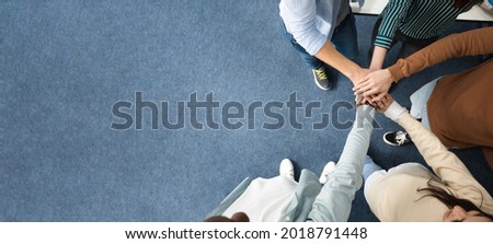 Teamwork And Unity Concept. Above top high angle view of young diverse group of people putting hands together standing in circle, celebrating collaboration and alliance. Panorama, banner, free space Royalty-Free Stock Photo #2018791448