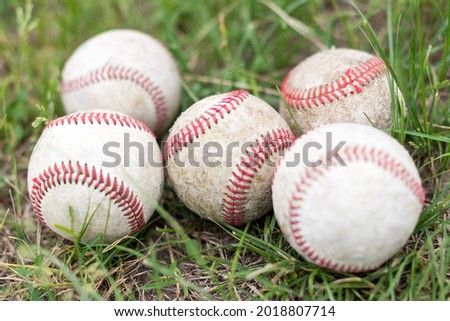 Close-up used baseballs on green grass field, sport concept.
