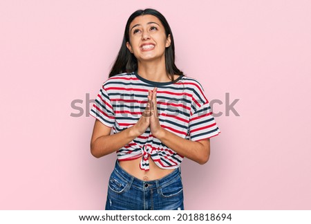 Young hispanic girl wearing casual clothes begging and praying with hands together with hope expression on face very emotional and worried. begging. 