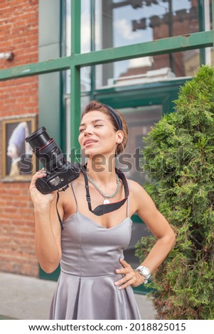 A beautiful girl photographer is engaged in shooting the area in the summer, walking around the big city