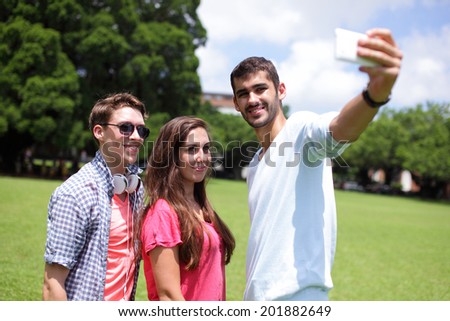Group of happy friends taking a selfie on a blue sky in campus lawn, caucasian