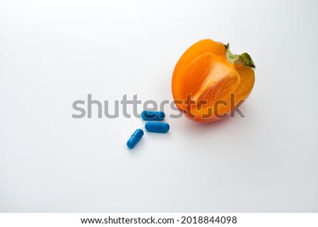 Persimmon and medicines on the table. White background. Strengthening the immune system. Pandemic protection.