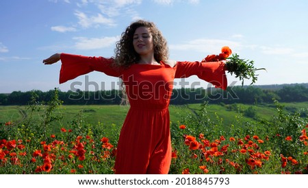 Inspired curly girl in straw hat on meadow with open arms looks at the camera, love in harmony with nature