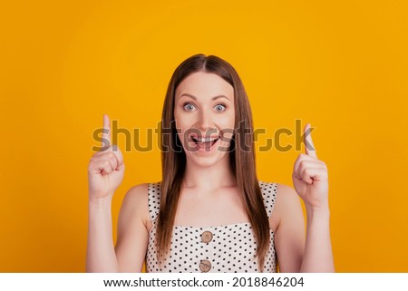 Portrait of excited promoter lady show fingers empty space on yellow background
