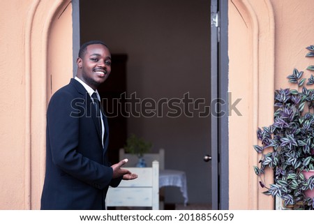 The restaurant and coffee shop owner is opening the door, inviting customers to his shop.Business african man standing and smiling