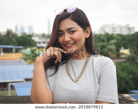 Close up portrait of a beautiful, young attractive and elegant Indian Asian woman against a white background  She is in casual attire and is smiling