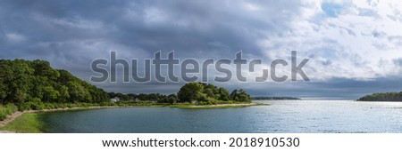 Panoramic seascape with views of islands under dramatic stormy clouds. Tranquil cove at Monk Park in Bourne, Massachusetts.