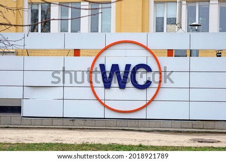 Large letters WC on facade of building. WC sign on the wall. Public toilet sign in a city park. International restroom symbol. Outdoor WC. 