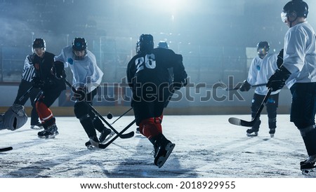 Ice Hockey Rink Arena: Professional Forward Player Breaks Defense, Hitting Puck with Stick to Score a Goal. Two Competitive Teams Play.