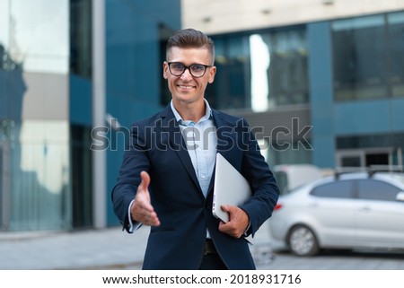 Business. Businessman Giving Hand For Handshake Welcome Gesture Adult Caucasian Male Business Person Holding Closed Laptop Give Hand Ready Handshake Office Building Background Royalty-Free Stock Photo #2018931716