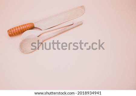 A closeup shot of wooden kitchen utensils isolated on pink background with copy space