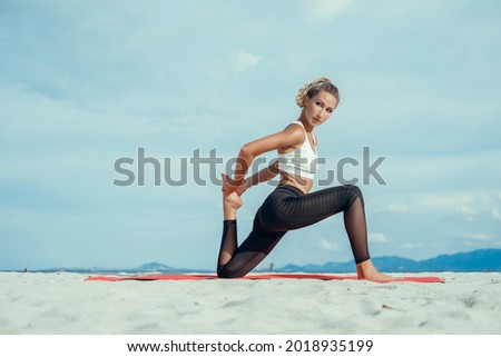 Young beauty woman Picture of young fitness lady outdoors in the beach make yoga stretching exercises,She is stretching exercises on shore at beach,meditation around sea  ocean at sunrise for health