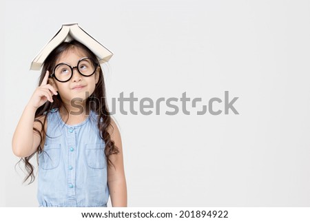 Portrait of little Asian child thinking and put a book on top with copy space Royalty-Free Stock Photo #201894922