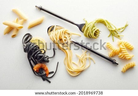 A top view of colored and classic spaghetti, noodles, and pasta on the white surf