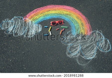 Children's drawing of a rainbow on the asphalt with crayons
