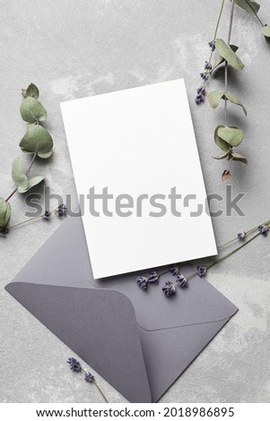Greeting or wedding invitation card mockup with envelope, lavender and dry eucalyptus twigs on grey, top view, copy space