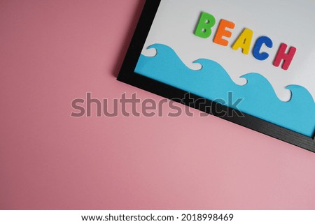 The colorful letters on a whiteboard with a copyspace with a summer vibe on a pink background