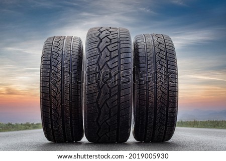 three tires in a summer sunset background. on asphalt. close up to the detailed tread. Lined up in order of importance. showing that tires used in summer with good grip, and safety for all the family. Royalty-Free Stock Photo #2019005930