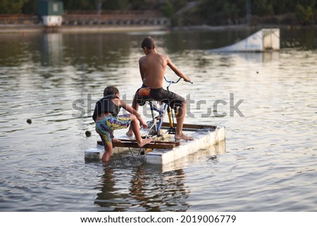 children playing at sunset in a lake on a pre-made bike with a pallet board and a system they invented