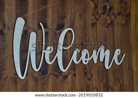 A word welcome with white font on a dark brown wooden door