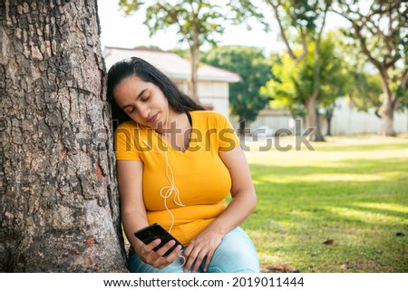 A closeup shot of a Hispanic woman holding her phone and sleeping