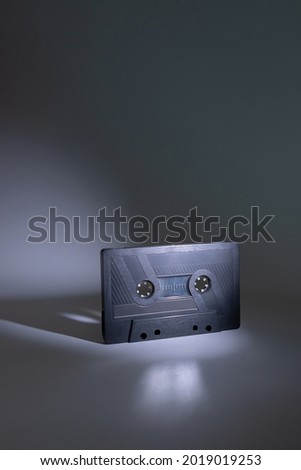 Audio cassette blurred on dark grey background with spot of light on it. Analog Audio Tape.