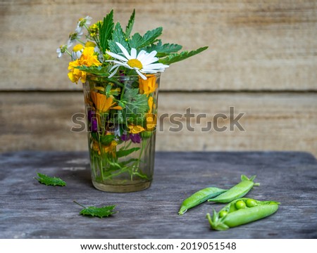 Tincture of flowers of medicinal plants in a glass of water and pods of young peas